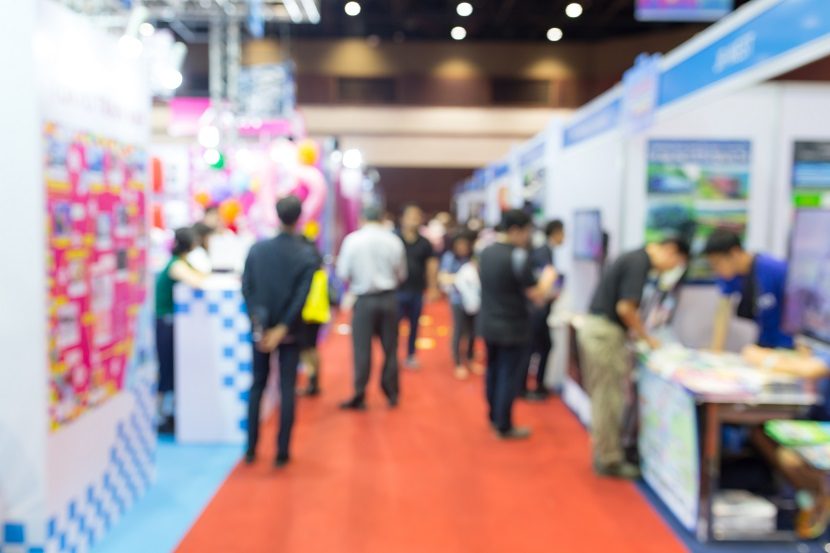 a blurry picture of people walking through a crowd at a trade show